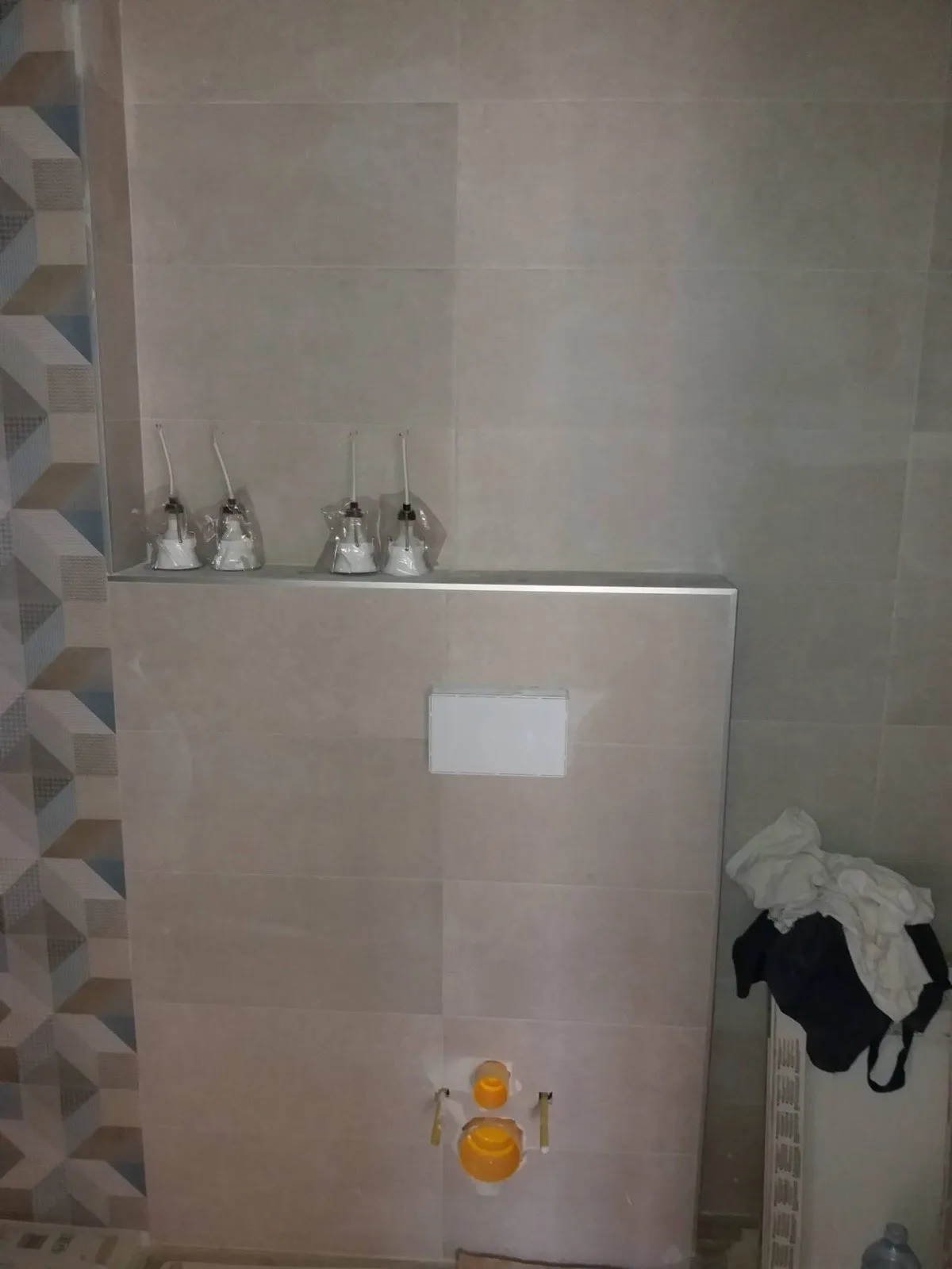 Baño reformado con cisterna empotrada, repisa de obra y alicatado decorativo geométrico