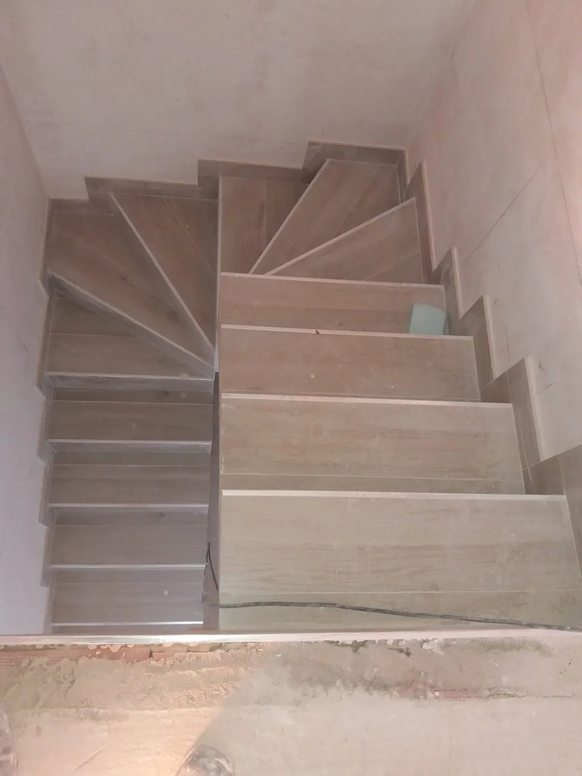 Escalera interior de caracol revestida con peldaños porcelánicos imitación madera