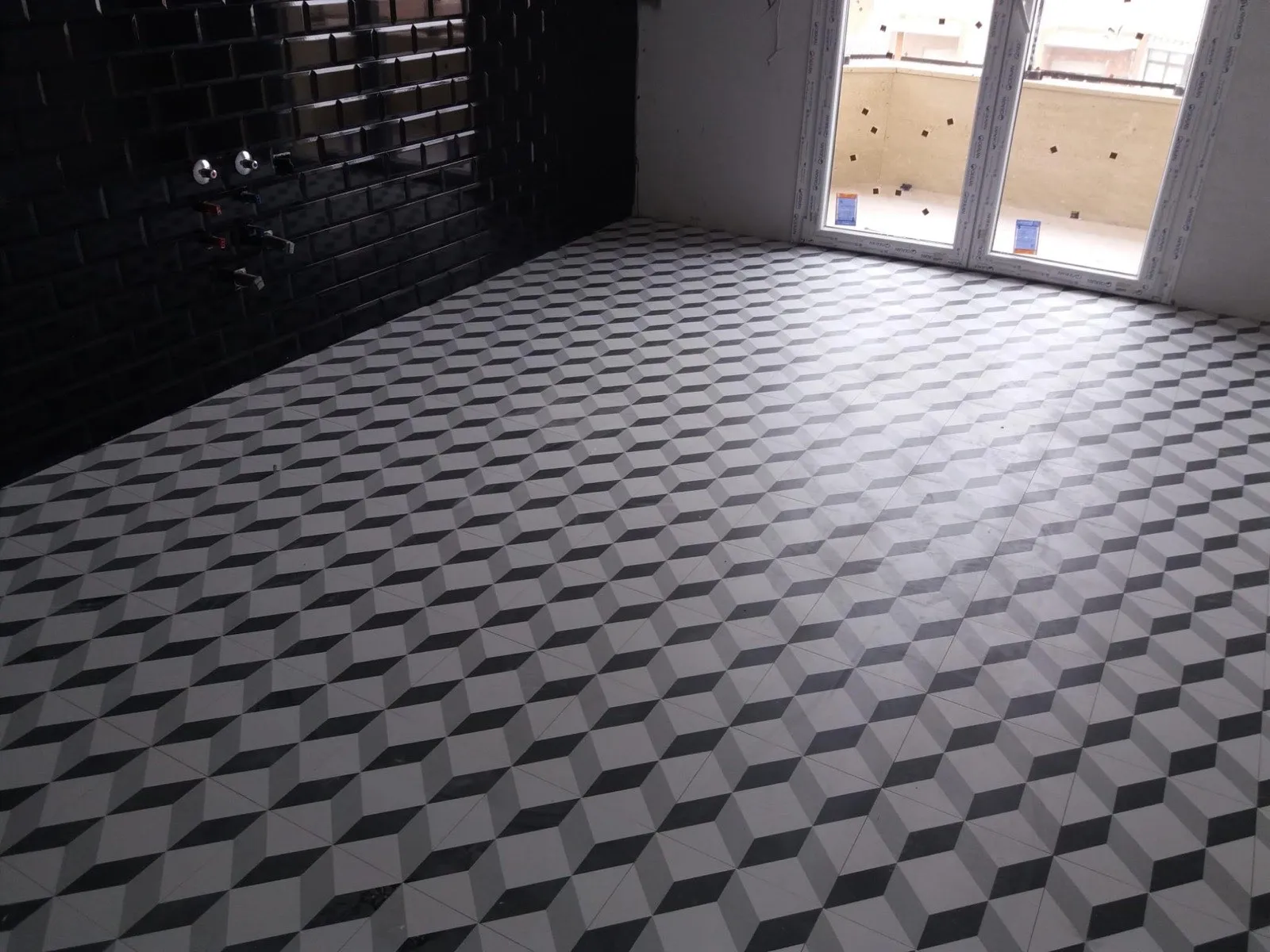 Suelo nuevo con baldosa hidráulica geométrica y pared de azulejo negro en reforma