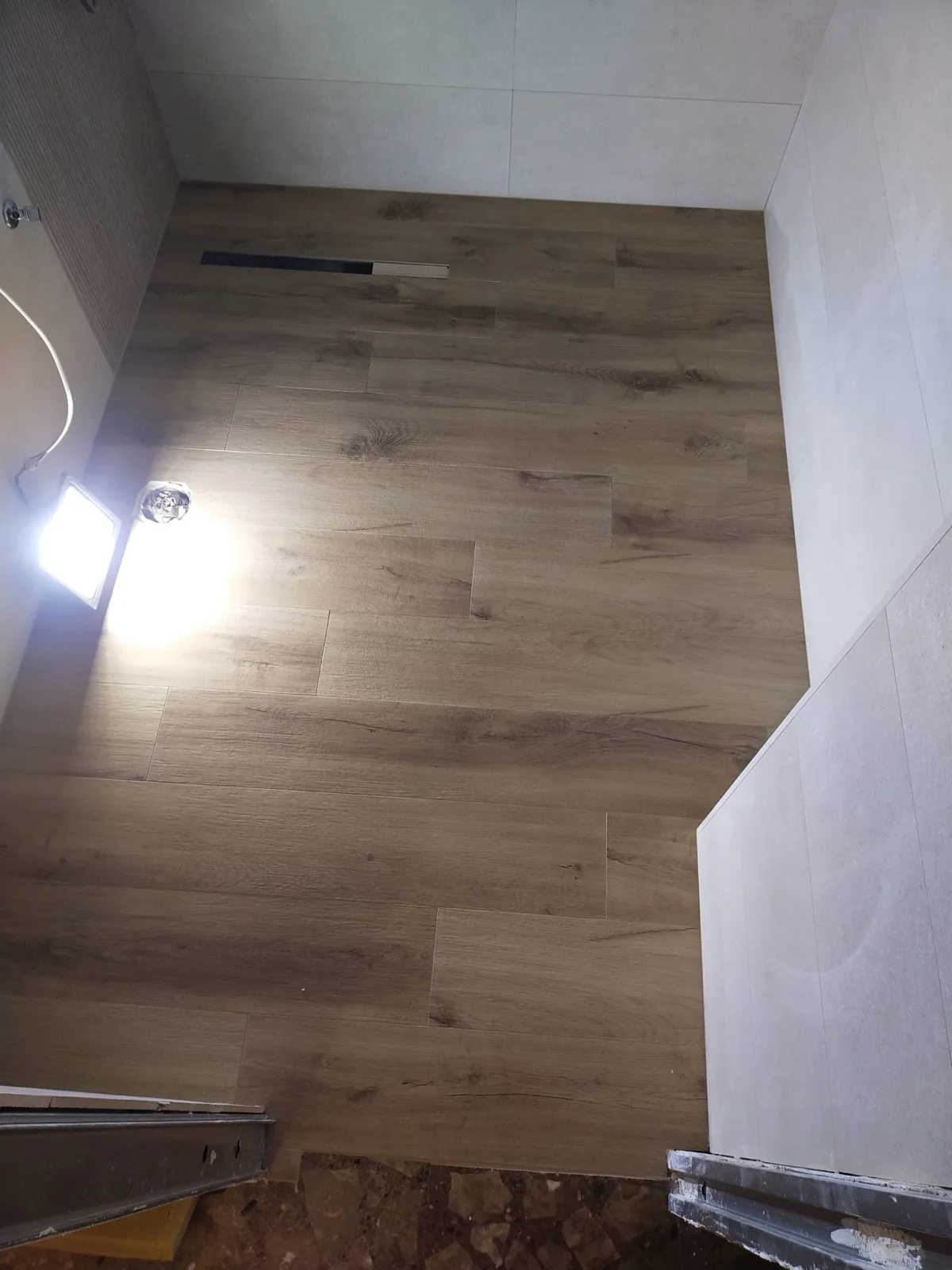 Colocación en proceso de pavimento porcelánico imitación madera en vivienda en obra