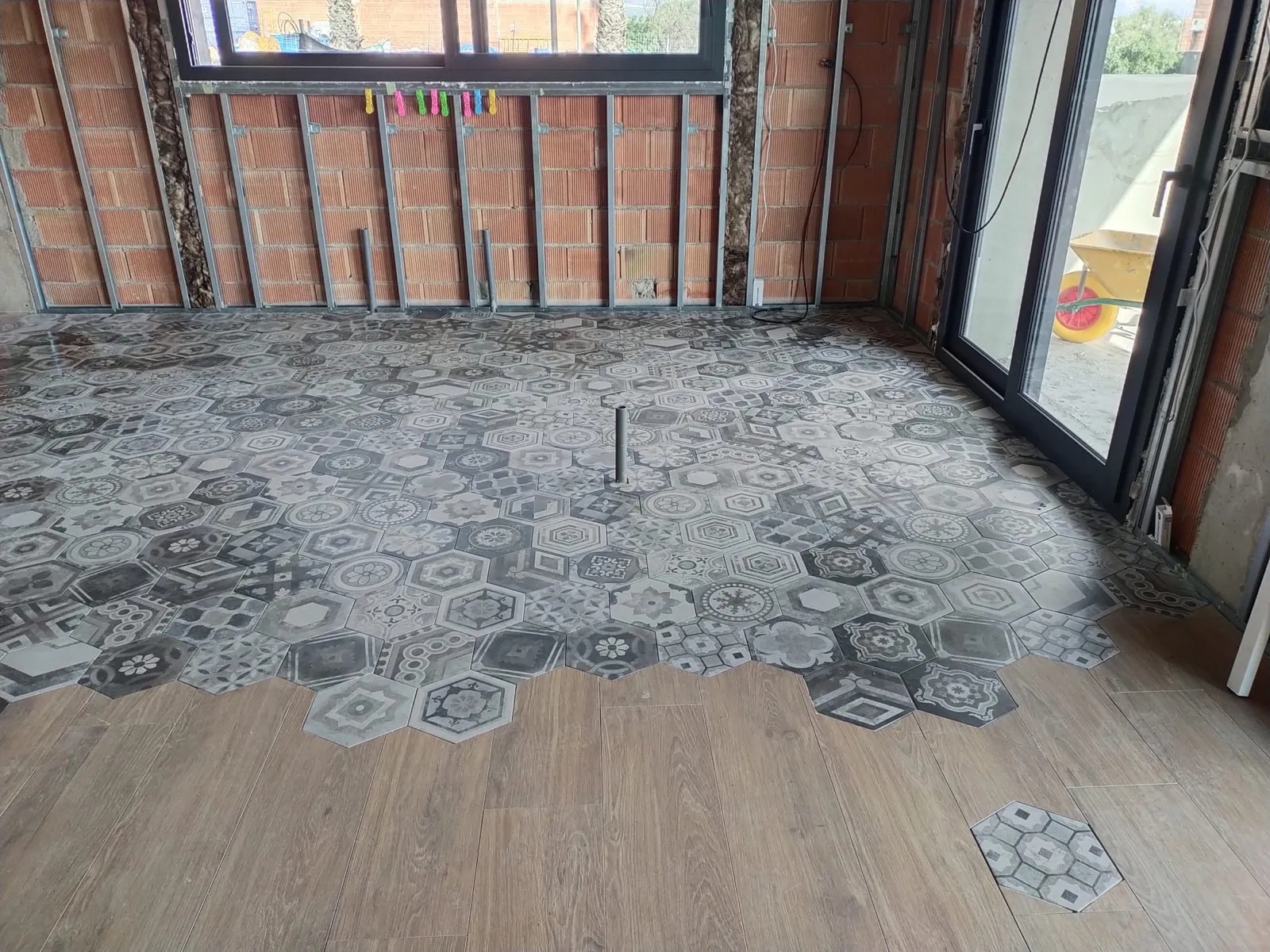 Suelo con baldosa hidráulica hexagonal combinada con porcelánico imitación madera en salón en obra