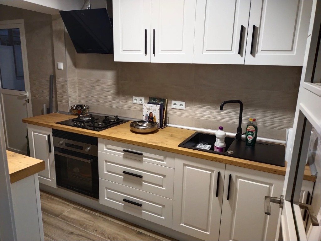 Cocina moderna reformada en Tarragona Centro con acabados en negro mate y barra de madera