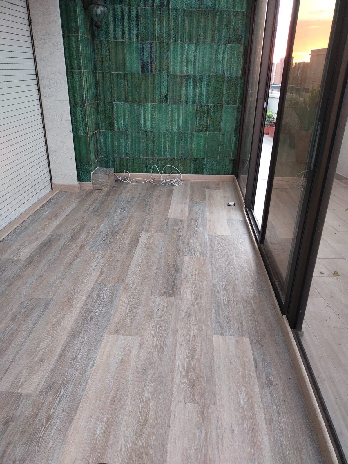 Terrassa reformada a Tarragona amb terra laminat i paret de rajola verda decorativa
