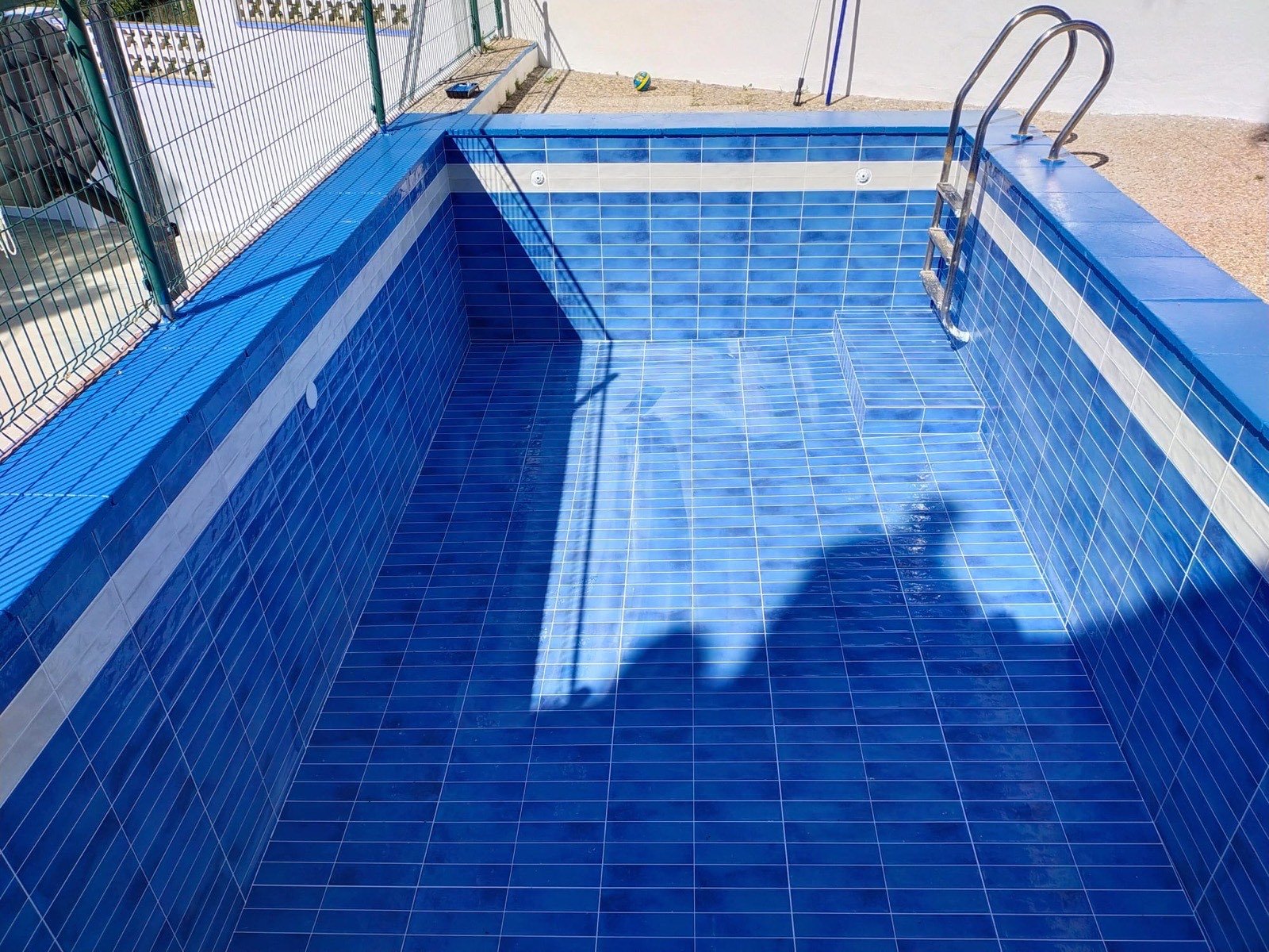 Piscina reformada amb enrajolat de gres blau i escala d'acer inoxidable